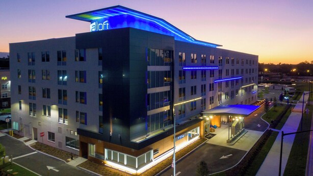 Et moderne hotel med fladt tag, flere etager og et tydeligt 'aloft'-skilt.