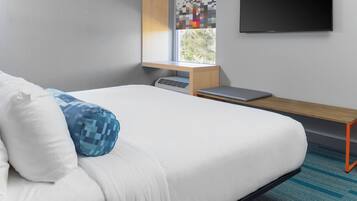 Una habitación de hotel moderna con cama, escritorio, televisión de pantalla plana y ventana con vistas.