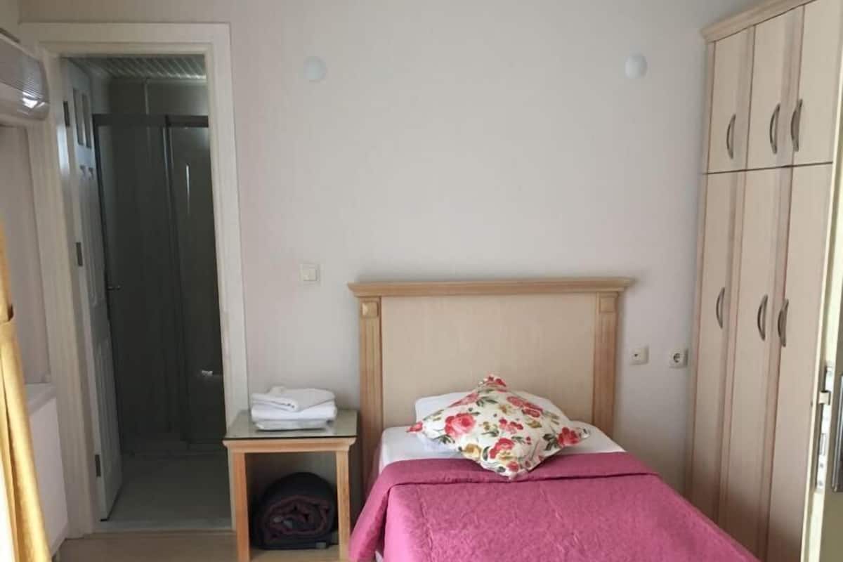 Une chambre à coucher comprenant un lit, une table de chevet, une armoire et une porte donnant sur une salle de bain.