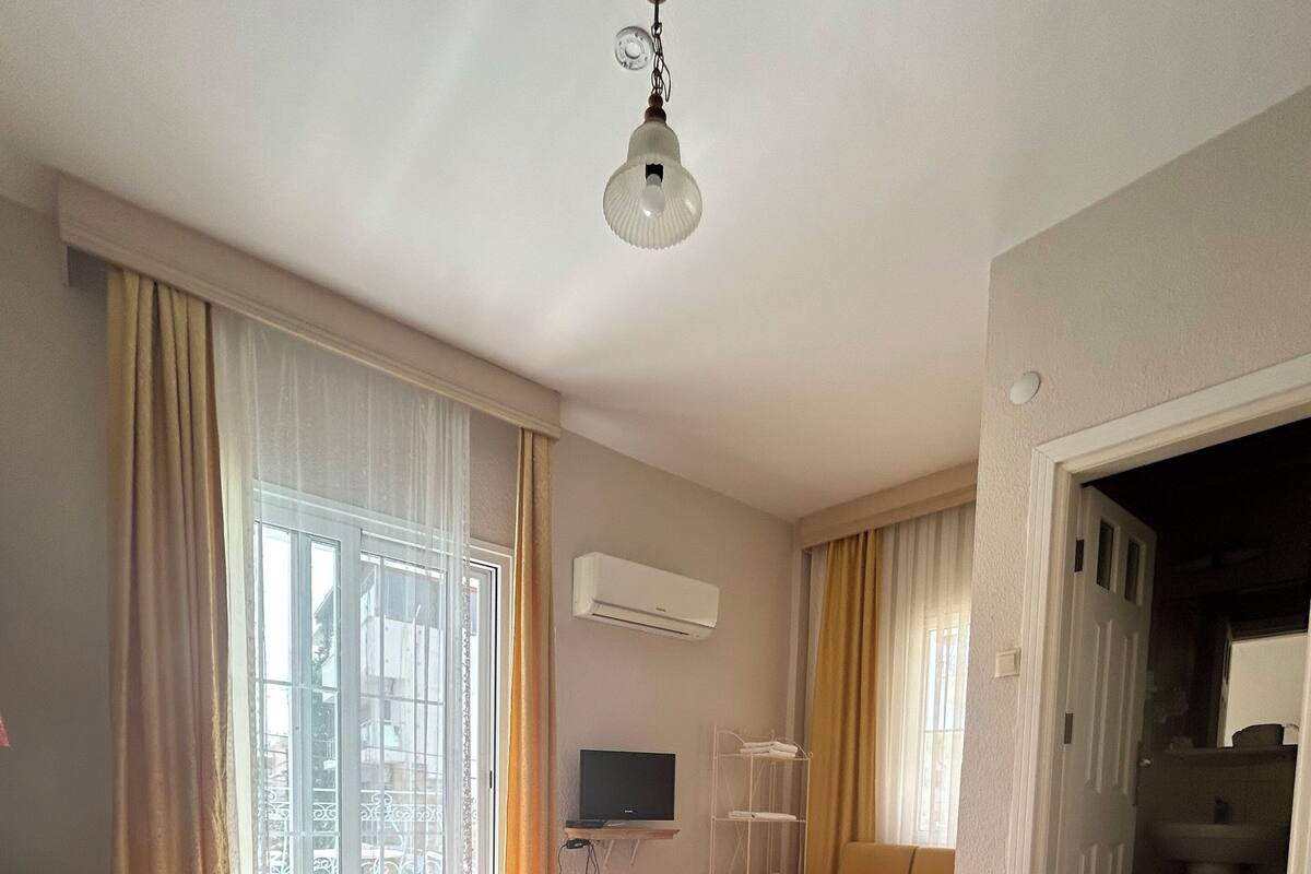 Une chambre d’hôtel avec un lit, une télévision et une fenêtre avec des rideaux.