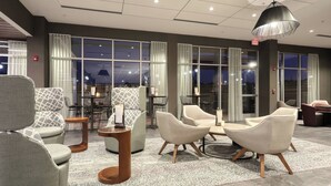 Eine moderne Lobby mit Sitzbereichen, großen Fenstern und einem Chandelier.