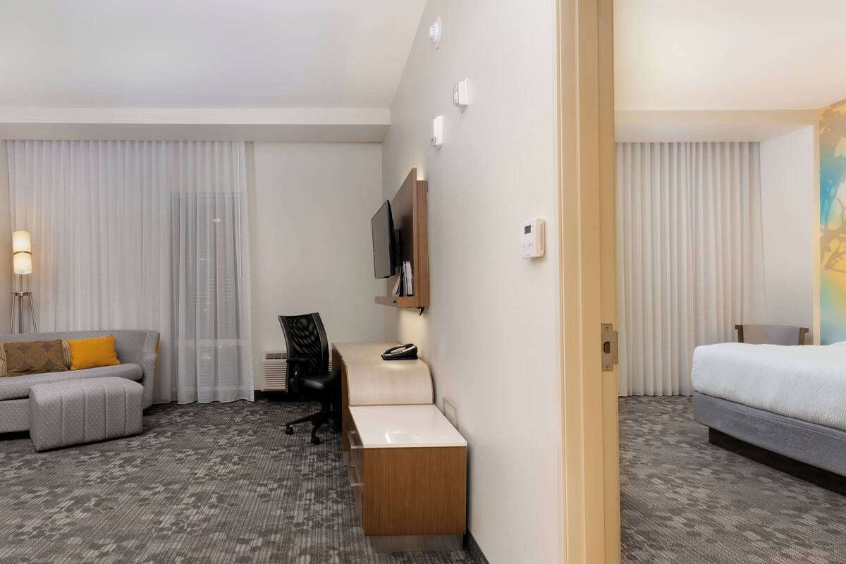 Una habitación de hotel con una cama, un escritorio, una silla, un sofá y un televisor.