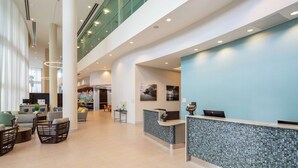 A spacious lobby with a reception desk, seating area, and a high ceiling with skylights. - DoubleTree by Hilton Miami - Doral, FL (Miami)