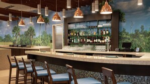 A bar area with a counter, bar stools, and a wall of liquor bottles. - DoubleTree by Hilton Miami - Doral, FL (Miami)