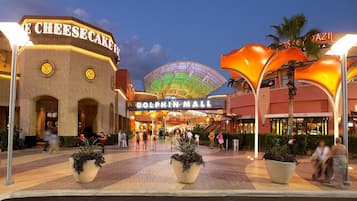 A shopping mall with a prominent 'Dolphin Mall' sign, a 'Cheesecake' store, and a large, illuminated dome structure.