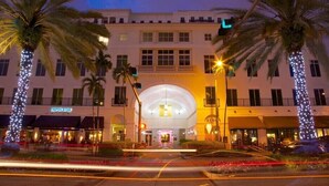 A hotel with a central atrium, palm trees, and a well-lit facade. - DoubleTree by Hilton Miami - Doral, FL (Miami)