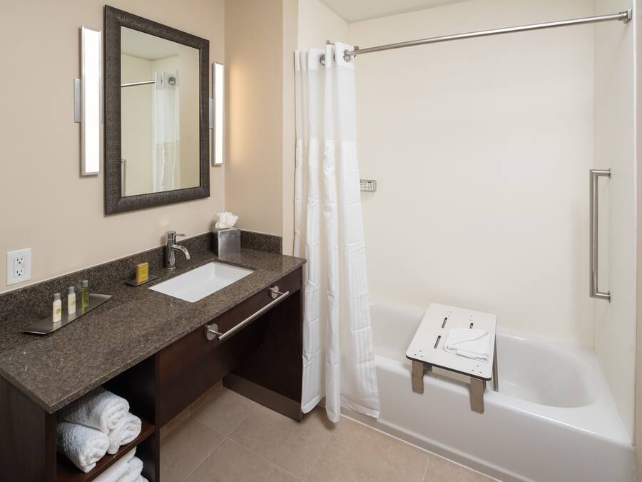 A bathroom with a sink, mirror, towel rack, and a shower with a curtain.