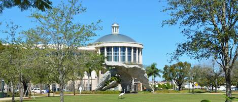 A large building with a dome and a unique rock formation sculpture in front.