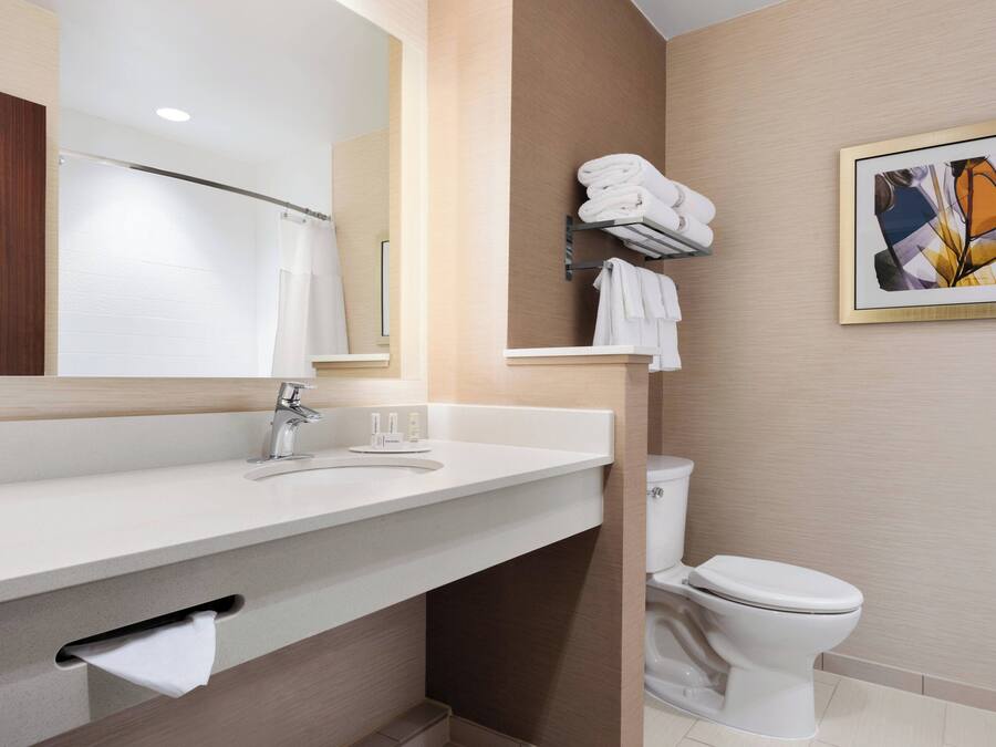 A modern bathroom with a white sink, a mirror, a towel rack, and a toilet.
