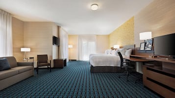 Une chambre d’hôtel avec un grand lit, un bureau, une chaise, un canapé et un téléviseur.