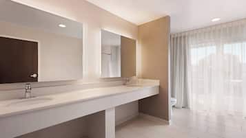 A modern bathroom with two sinks, a large mirror, and a toilet.