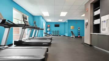 A gym with treadmills, exercise balls, and a water dispenser.