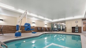 A modern indoor pool with clear water, a blue pool chair, and a lifeguard stand. - Fairfield Inn & Suites by Marriott Charlottesville Downtown/University Area (Charlottesville)