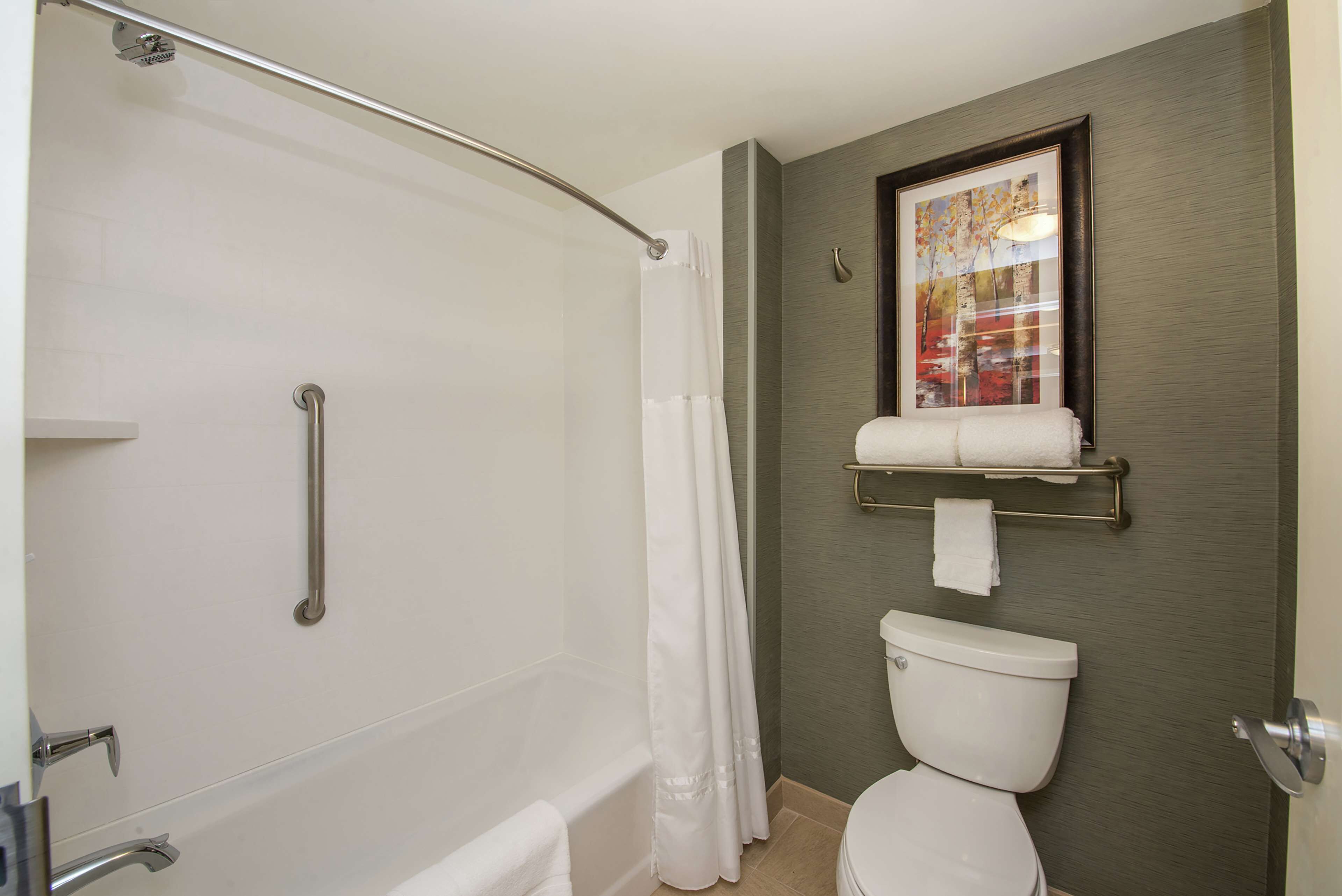 A bathroom with a bathtub, a toilet, a shower curtain, and a towel rack.