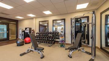 A gym with weightlifting equipment, exercise balls, and dumbbells.