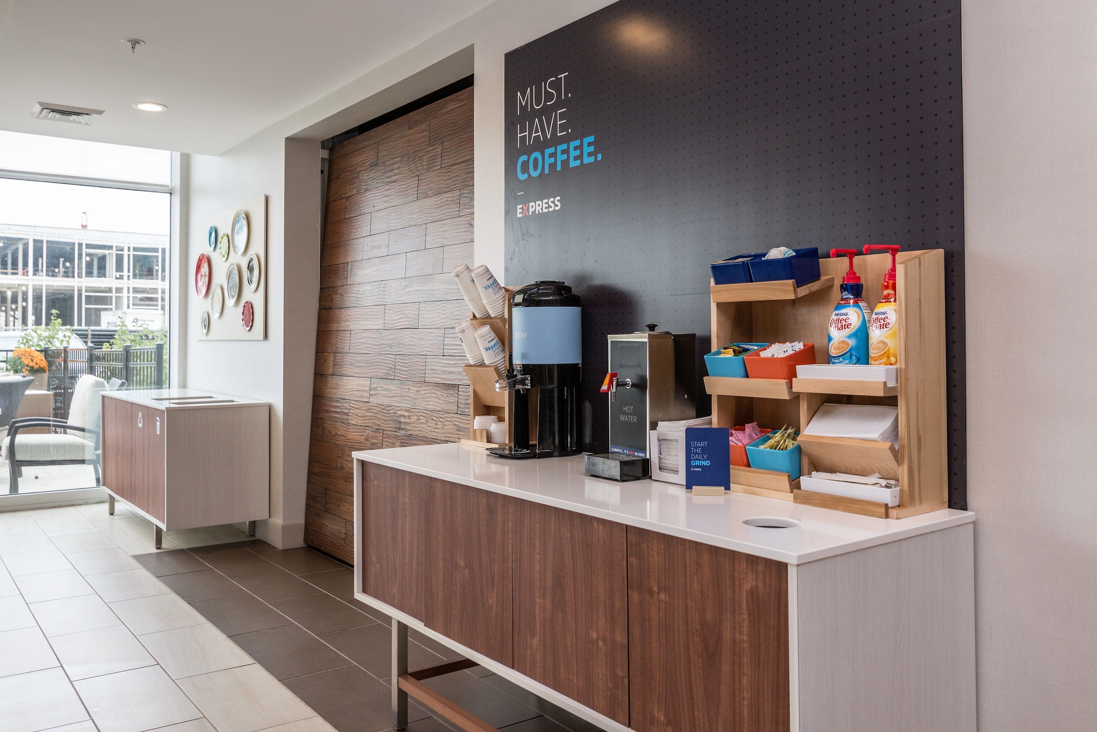 A modern coffee station with a coffee machine, water dispenser, and storage for coffee beans and milk.