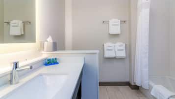 A bathroom with a large sink, a mirror, a towel rack, and a shower curtain.