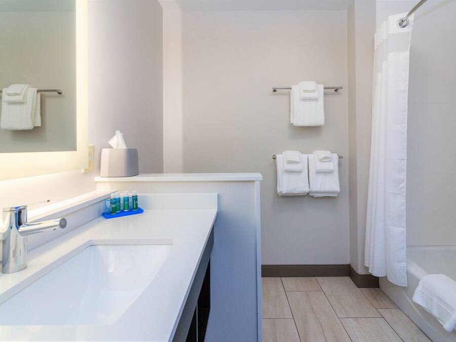 A bathroom with a large sink, a mirror, a towel rack, and a shower curtain.