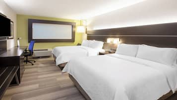 Quarto de hotel com duas camas, uma escrivaninha, uma cadeira, uma TV e um telão projetor.