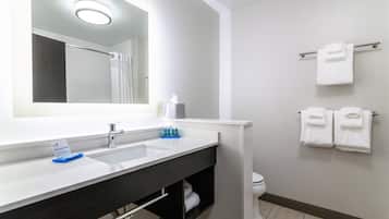 Un bagno con un ampio specchio, due lavandini, un portascopevoli con asciugamani e un water.