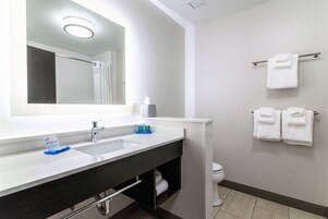 Un baño con un espejo grande, dos lavamanos, un tendedero de toallas con toallas y un inodoro.