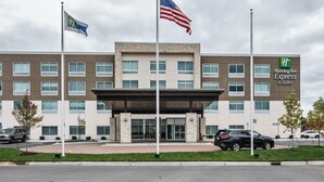 A Holiday Inn Express & Suites hotel with a modern architectural design, featuring a prominent entrance and multiple flags. - Holiday Inn Express & Suites Allen Park by IHG (Allen Park)