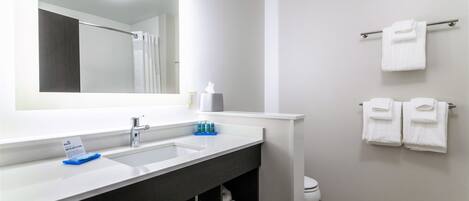 A modern bathroom with a white sink, dark vanity, and a towel rack with two towels.