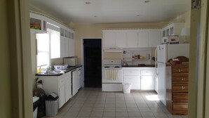 Una cocina compacta con muebles blancos, un microondas, una estufa y un refrigerador.