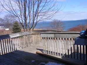 Une terrasse en bois offrant une vue sur un plan d’eau et des arbres.