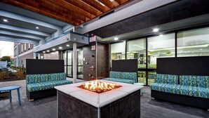 An outdoor seating area with a fire feature, two sofas, and a table. - Home2 Suites by Hilton Fort Worth Fossil Creek (Fort Worth)