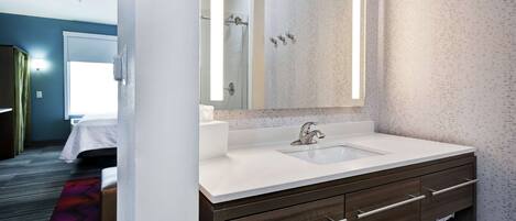 Un baño moderno con un lavamanos blanco, tocador de madera oscura y un espejo grande.