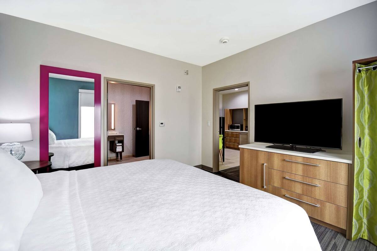 Hotelkamer met een bed, een televisie, een bureau met stoel, en een badkamer zichtbaar door een geopende deur.