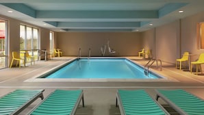 Une piscine entourée de chaises longues et de chaises jaunes.