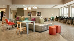Un espace de détente moderne comprenant un canapé, des fauteuils, une table et des poufs.