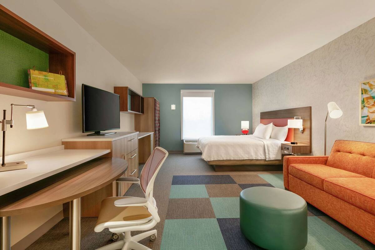Een hotelkamer met een bureau, stoel, bed en een bank.