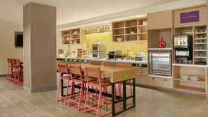 Un espace cuisine moderne avec un îlot central, des chaises rouges et un réfrigérateur.
