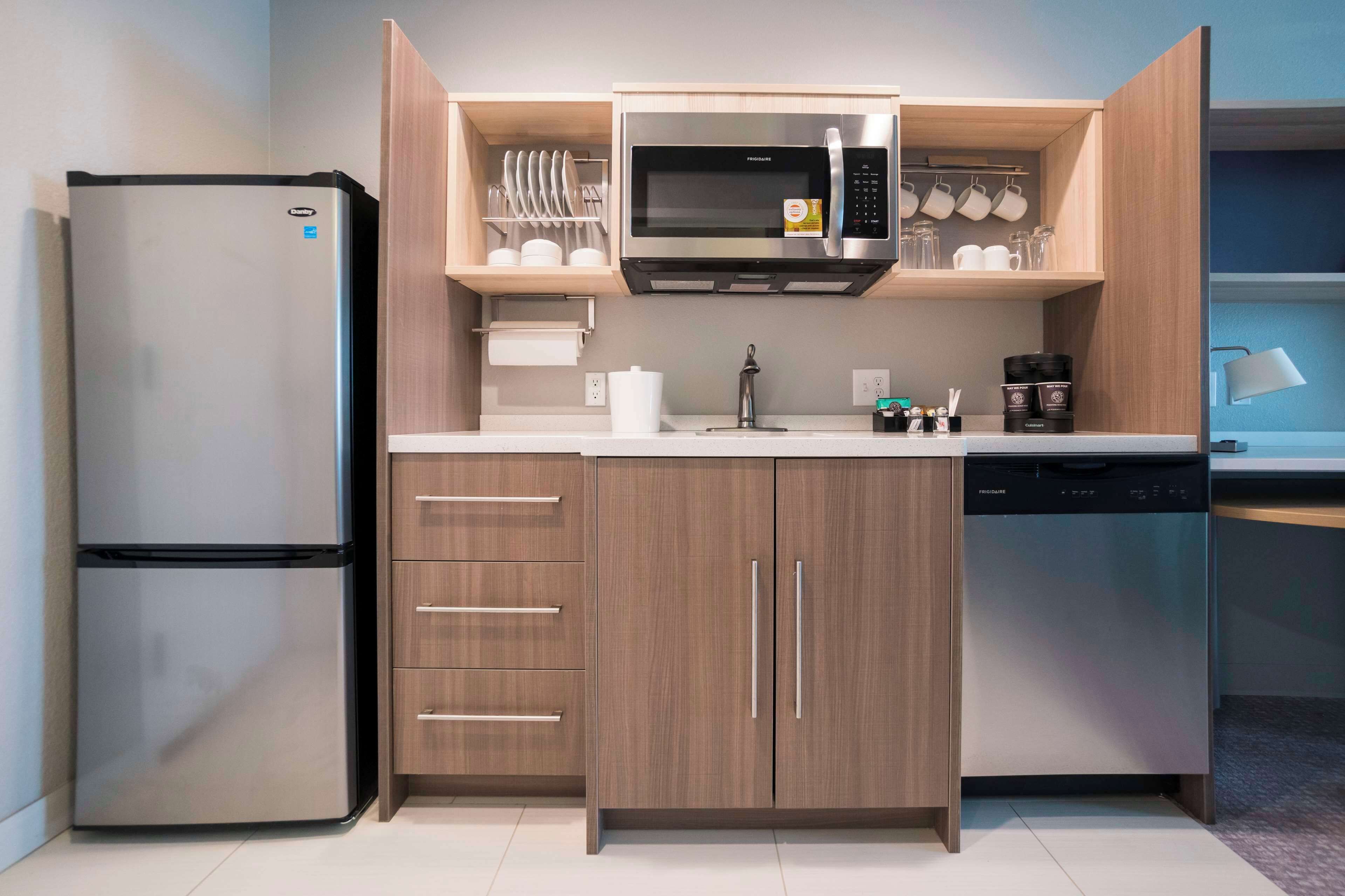 A compact kitchen with a built-in microwave, a refrigerator, and a dishwasher.