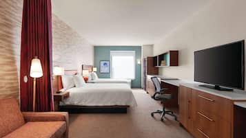 A hotel room with two beds, a desk with a TV, a chair, and a sofa.
