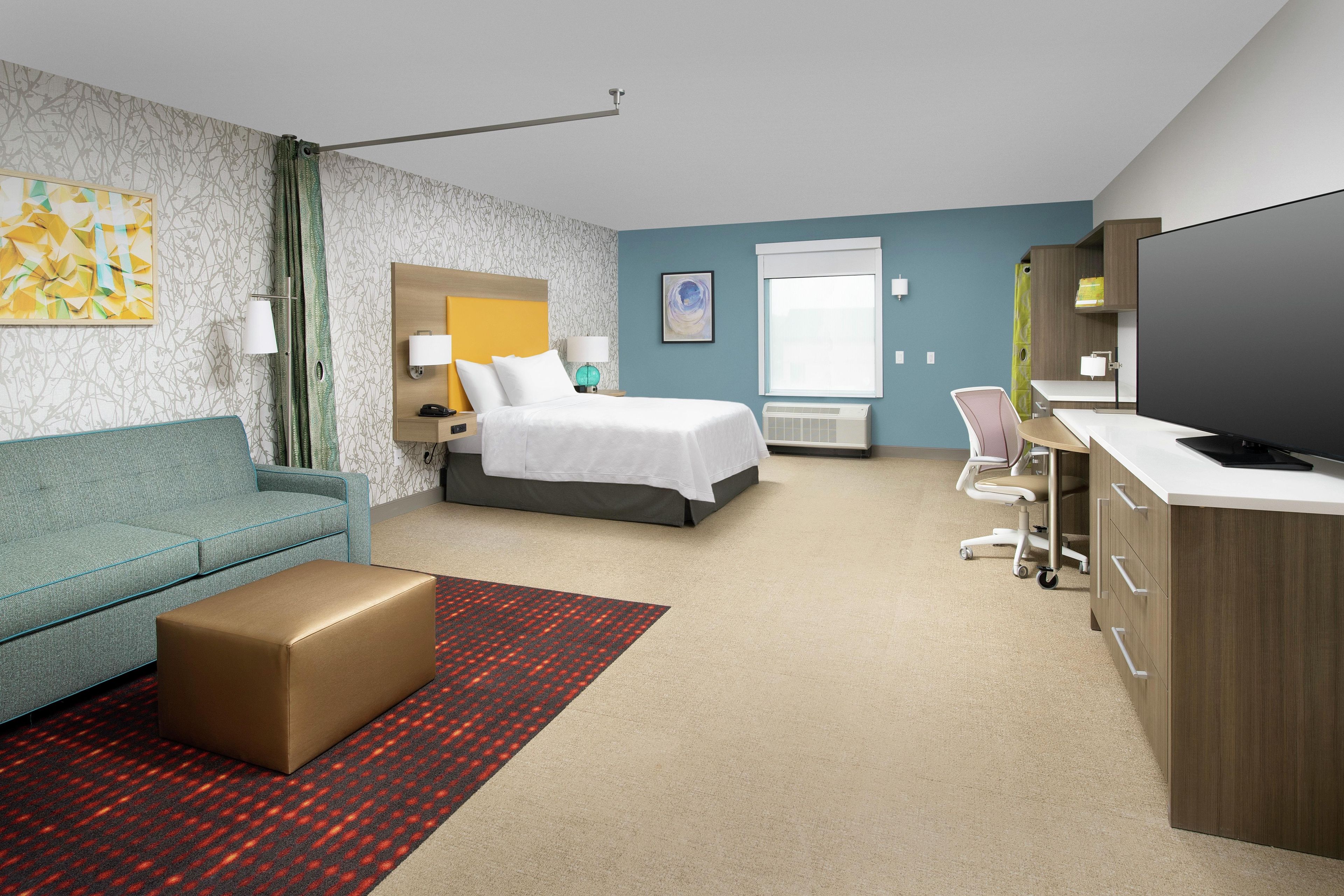 Une chambre d’hôtel comprenant un lit, un canapé, un bureau, une télévision et une salle de bain.
