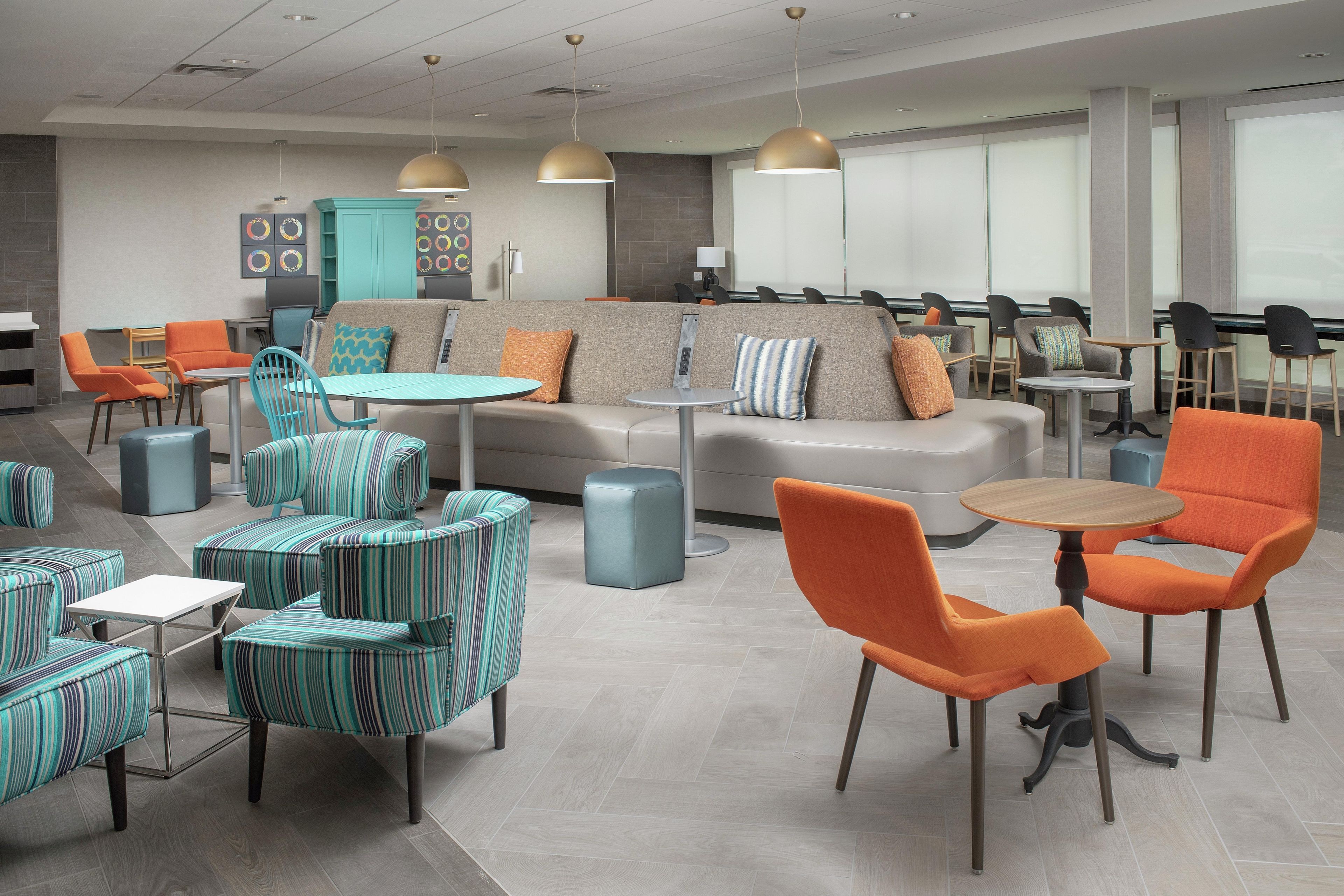 A modern lounge area with seating arrangements, tables, and pendant lighting.