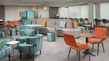 A modern lounge area with seating arrangements, tables, and pendant lighting.