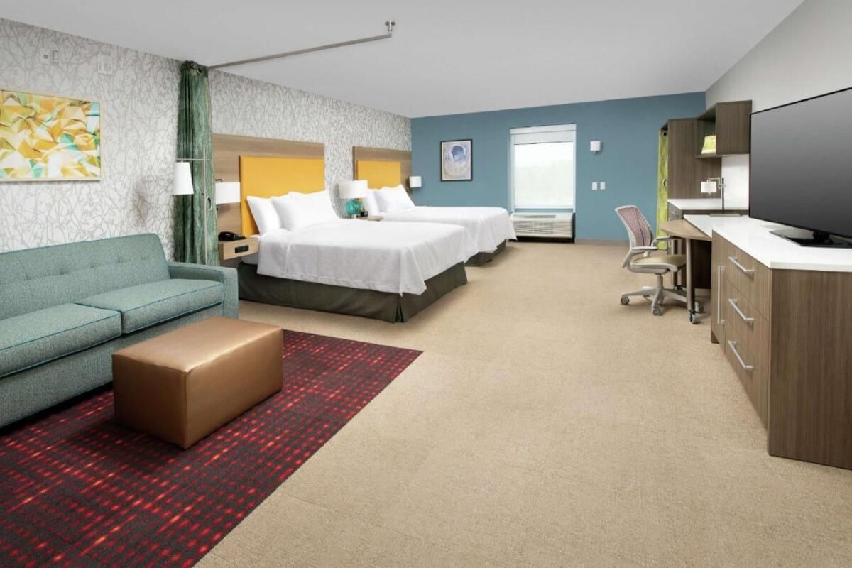 A hotel room with a bed, a sofa, a desk, and a television.