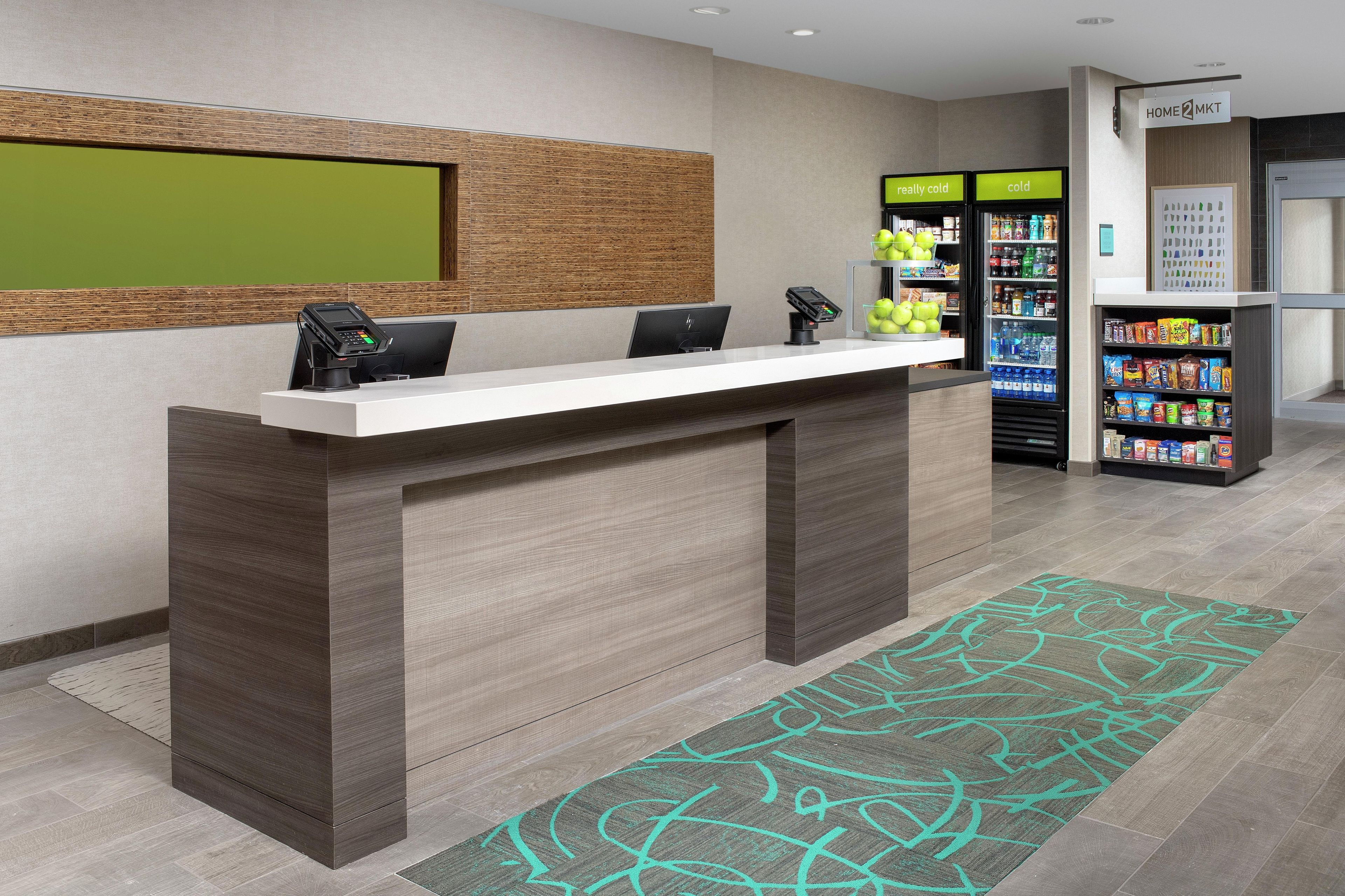 A reception desk with a counter, two chairs, a wall-mounted phone, and a vending machine with a sign indicating 'really cold' and 'cold' options.