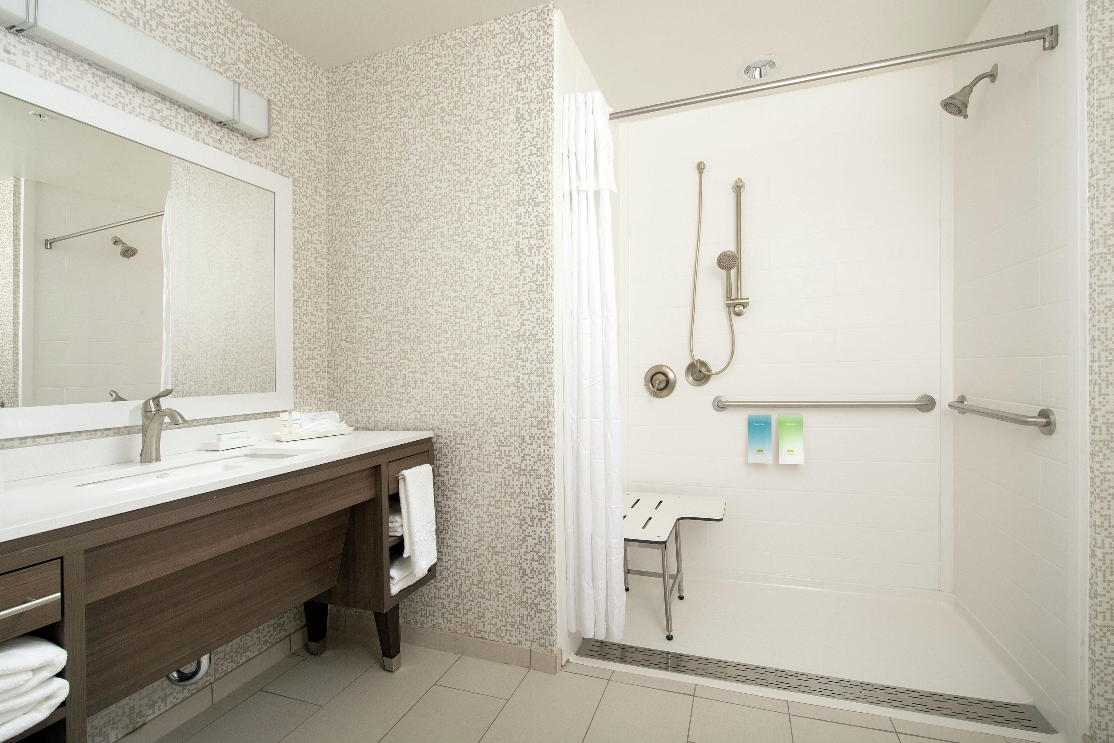A bathroom with a shower, a sink, and a mirror.