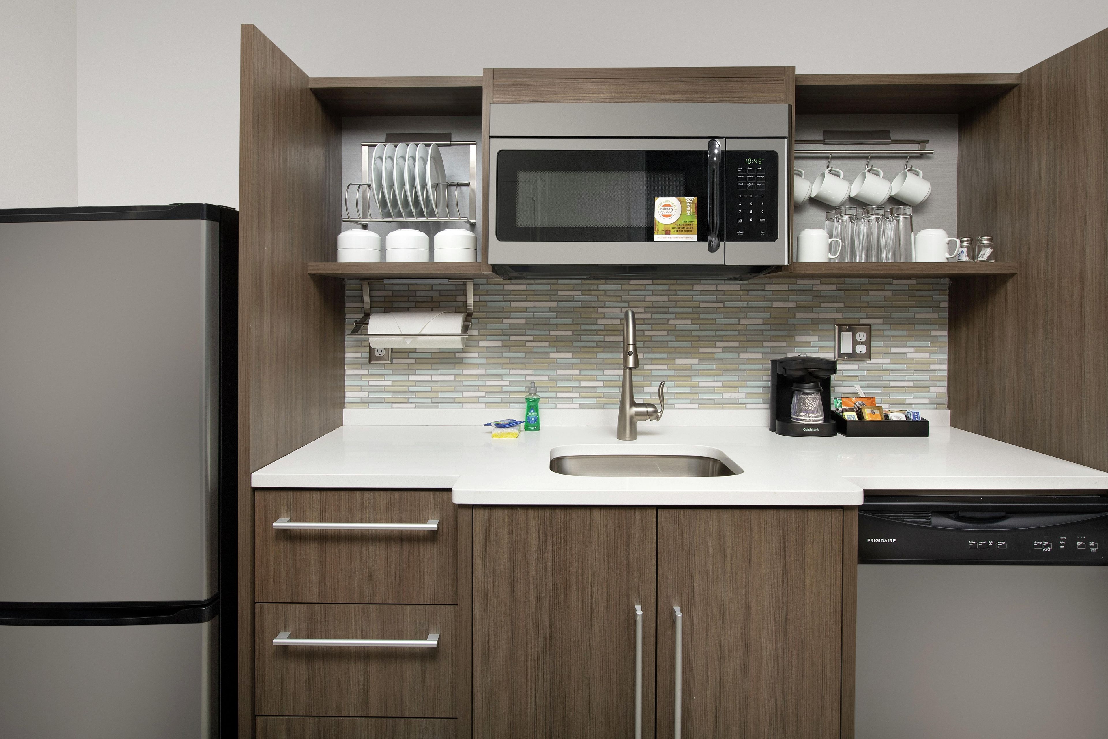 A compact kitchen with a built-in microwave, a sink, and a dishwasher.