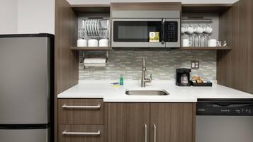 A compact kitchen with a built-in microwave, a sink, and a dishwasher.