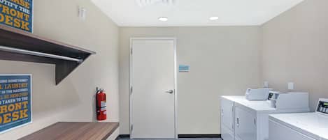 Un cuarto de lavandería con extintor, una puerta y un letrero en la pared.