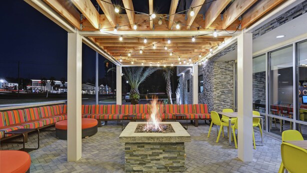 An outdoor patio with a fire pit, seating, and a pergola with string lights. - Home2 Suites by Hilton Richmond Hilll Savannah I-95 (Richmond Hill)