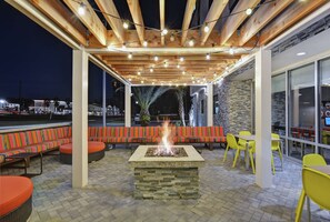 An outdoor patio with a fire pit, seating, and a pergola with string lights. - Home2 Suites by Hilton Richmond Hilll Savannah I-95 (Richmond Hill)