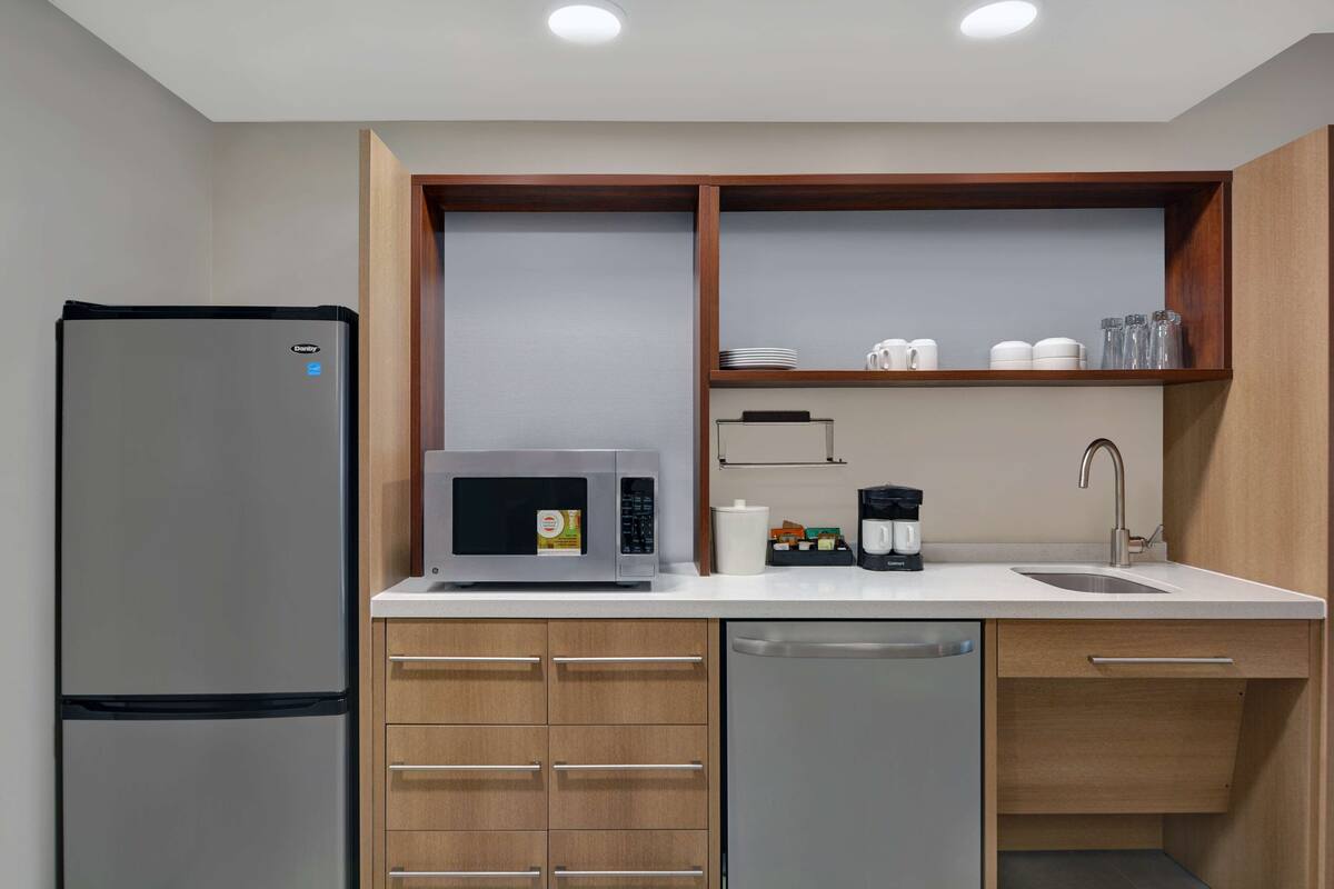 A modern kitchen with a refrigerator, microwave, coffee maker, and dishwasher.